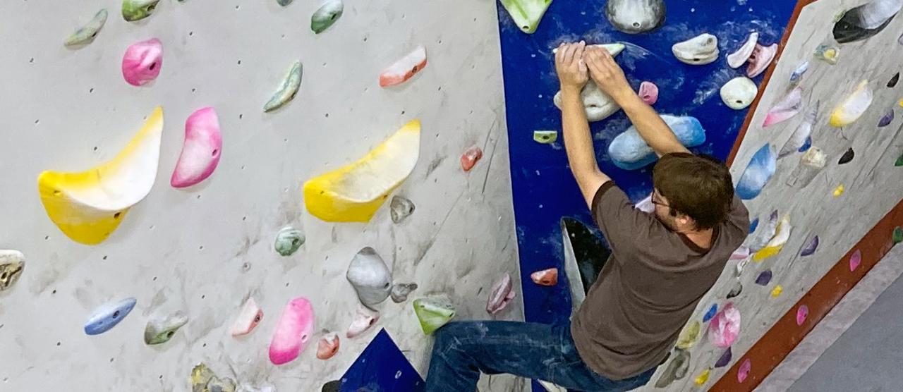 Close-up image of a male student climbing a bouldering wall